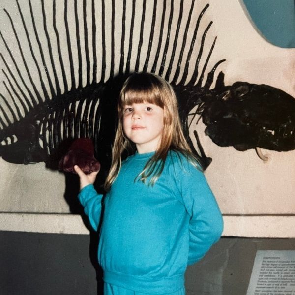 une photo de la jeune Isabelle Popp, posant devant un fossile de Dimetrodon