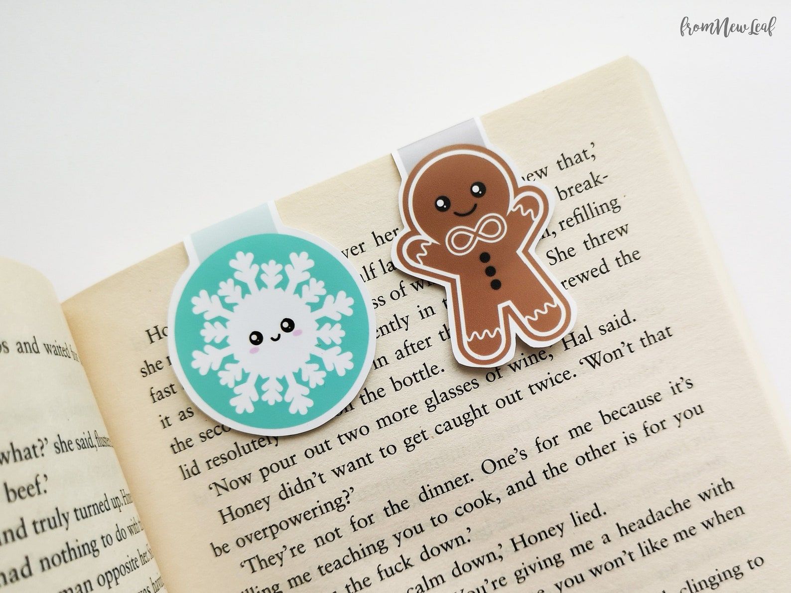 Image of a set of magnetic bookmarks. On the left is a snowflake with a green background and on the right, a decorated gingerbread man. 