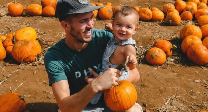 image of man holding baby in pumpkin patch
