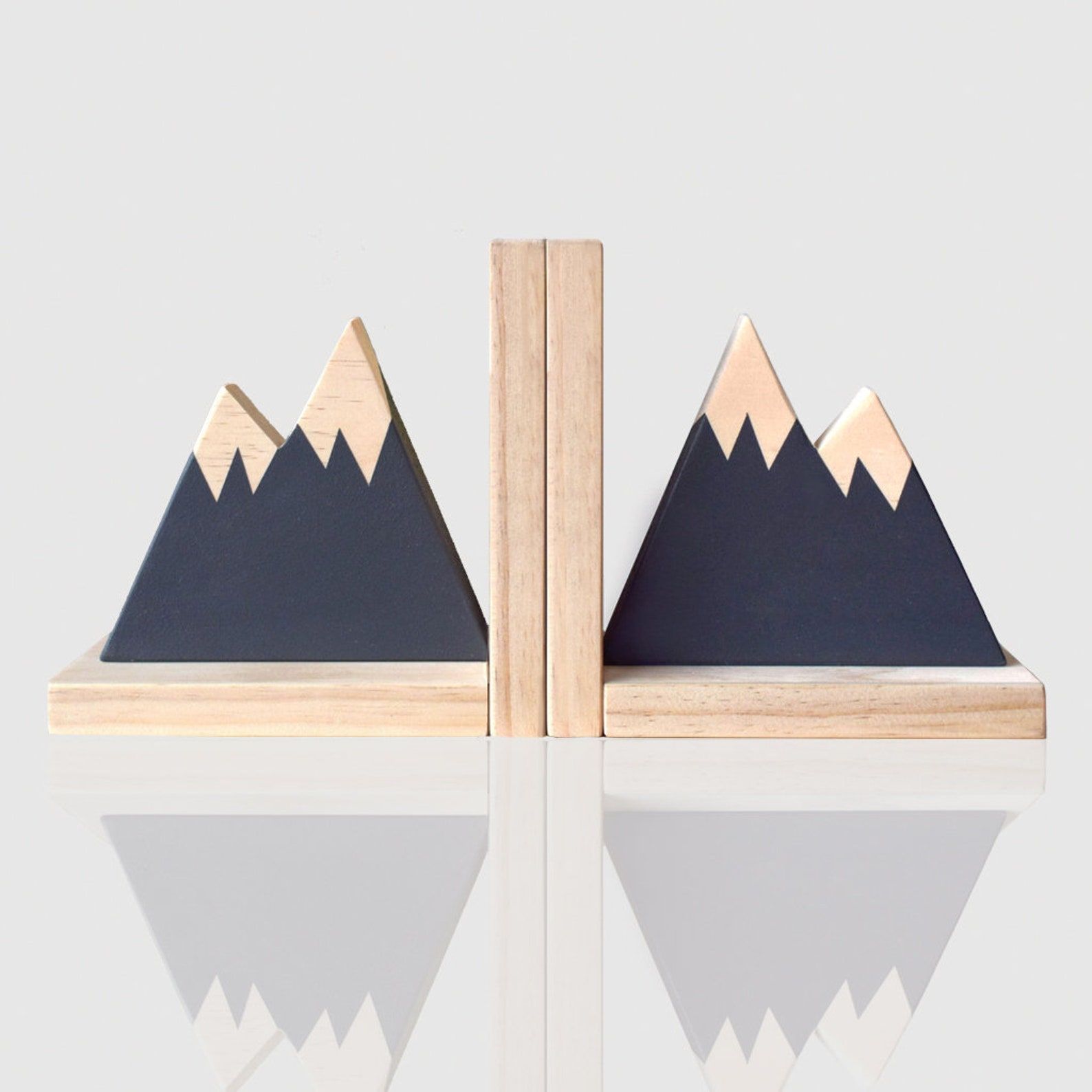 Two wooden bookends in the shape of mountain peaks. The mountains are painted navy blue while the peaks and base are a natural wood finish.