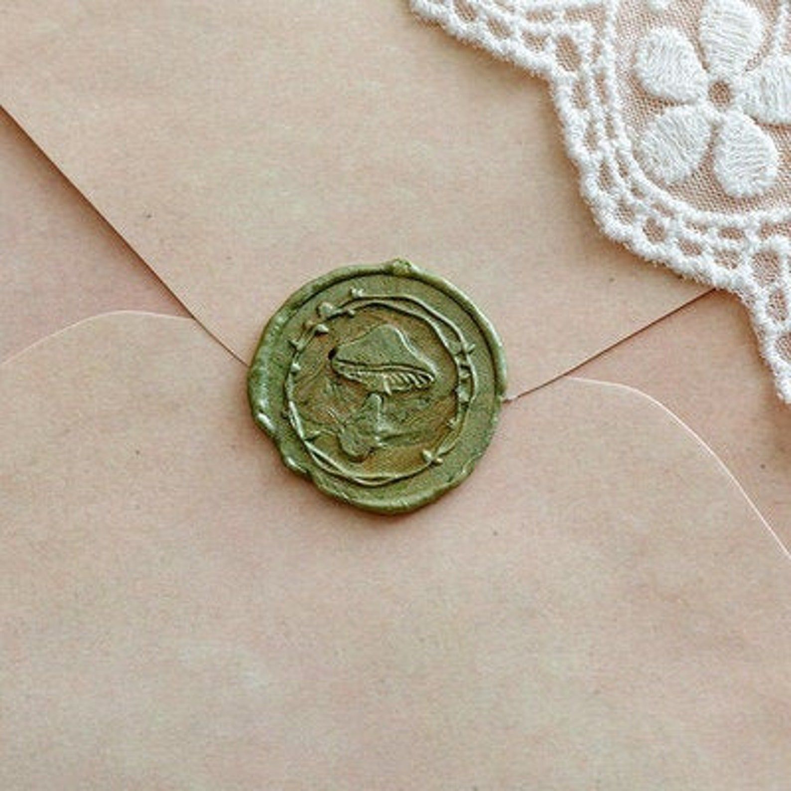 Image d'un sceau de cire verte sur une enveloppe en manille.  Le timbre comporte un gros champignon. 