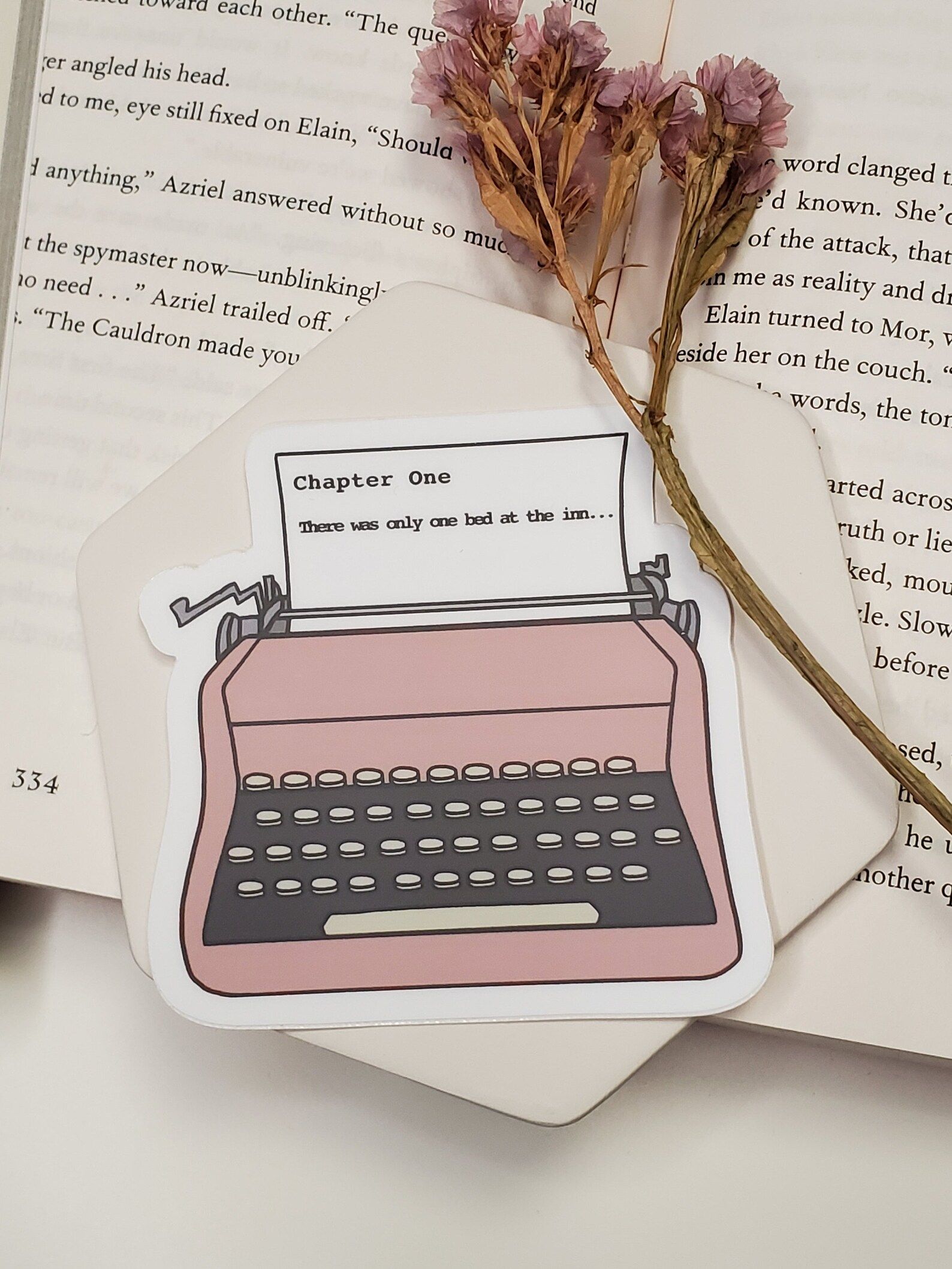Pink typewriter sticker. The paper inside the typewriter reads "Chapter One: There was only one bed at the inn..."