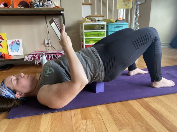 author reading while in supported bridge pose