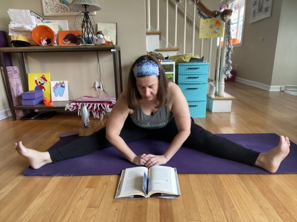 author reading while in a seated, wide-legged forward fold