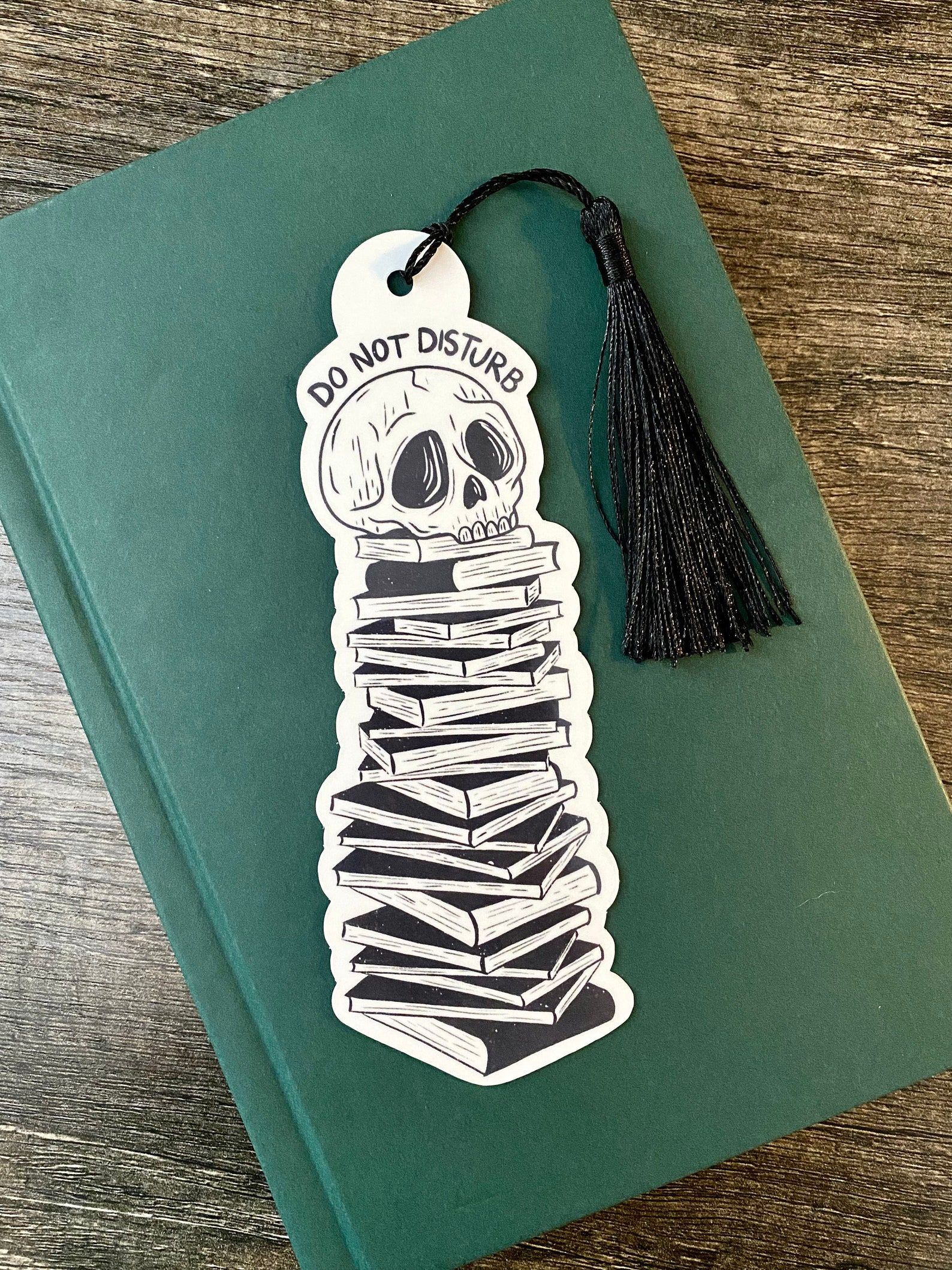 A bookmark featuring a stack of books with a skull on top and the words 