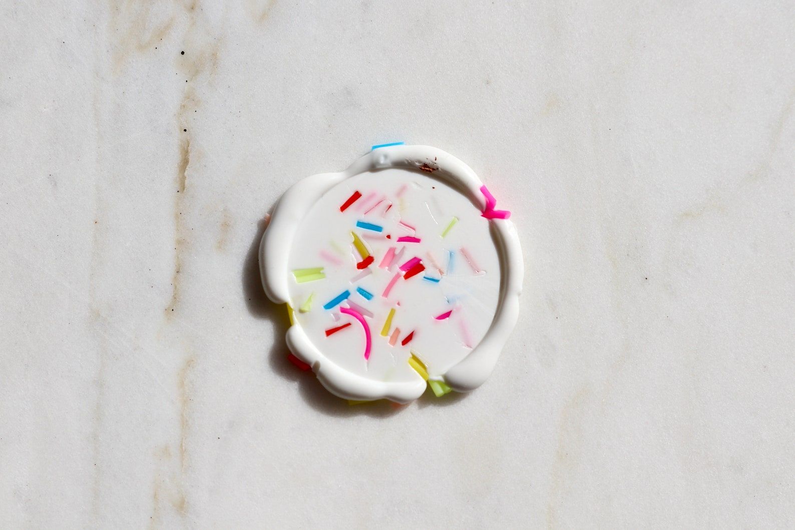 Image of a wax seal sticker. It's white with sprinkles. 