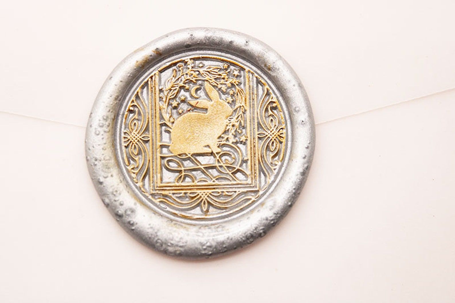 Image d'un cachet de cire en argent.  Il est en or à l'intérieur avec une image d'un lapin à l'intérieur d'une carte de tarot. 