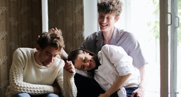 two men and a woman cuddled up and laughing together