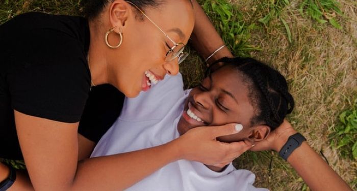 two Black women snuggling in the grass