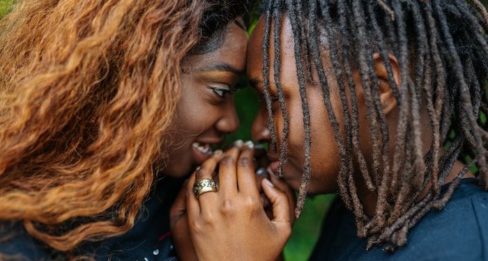 two Black women staring into each others eyes and holding hands