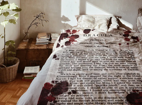 white blanket with red blood splatters and the first page of Dracula