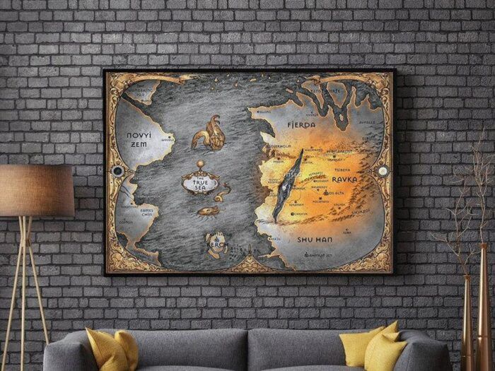 A map of the Grishaverse in shades of gold and grey. Much of Ravka is depicted in vibrant gold, while the Fold is a charcoal grey slice into the landscape. The True Sea is labelled with an ornate plate and the edges of the map are drawn with a gilt effect.