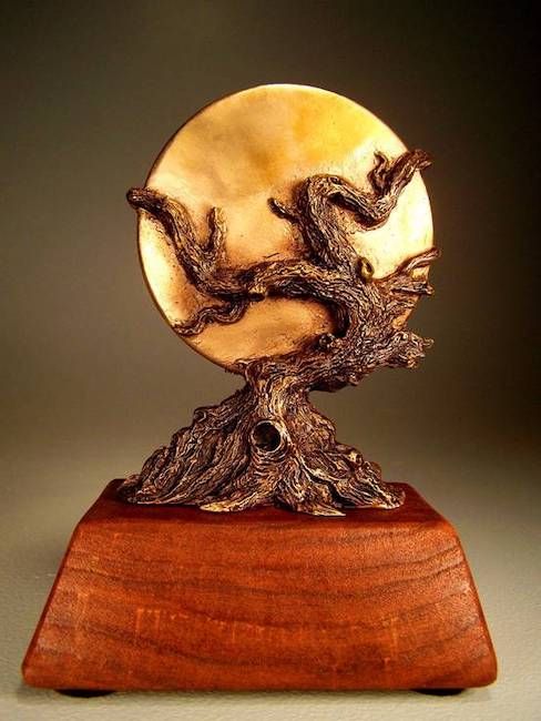 La statue du prix World Fantasy.  Il s'agit d'une base trapézoïdale en bois de nounours avec un arbre noueux tenant une lune dorée. 