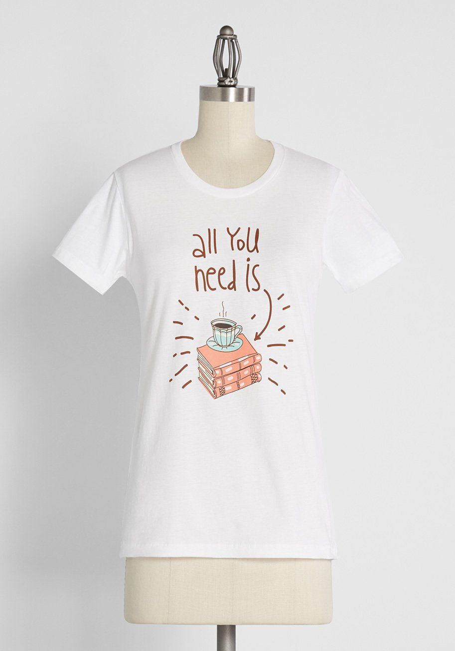 Image of a white shirt. In the center is a stack of books with a tea cup. Text reads "All You Need Is," with an arrow pointing to the image. 