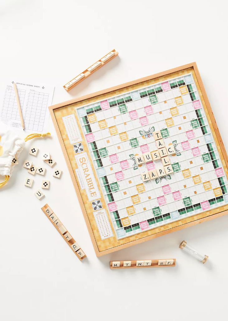 A Scrabble board with light wood accents, in yellow, green, and pink.