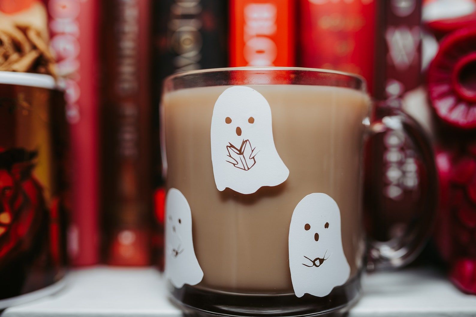 image of a clear glass mug with white ghosts reading books. 
