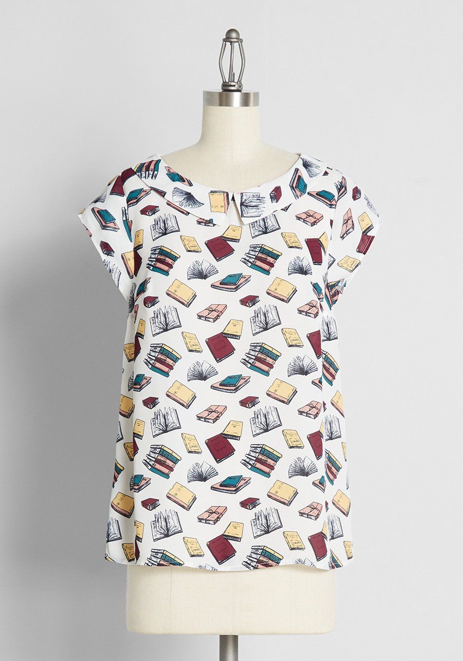 Image of a white collared top with a book pattern all over it. 