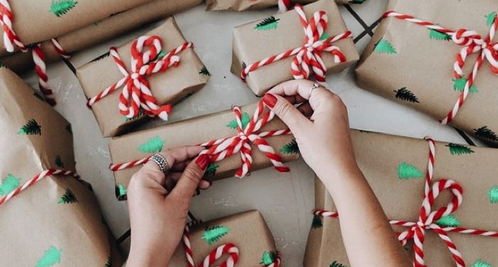 gifts being wrapped by a hand with red nail polish