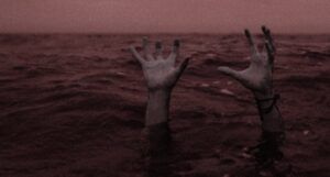 the hands of a drowning person coming out of a body of water