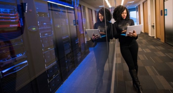 image of a Black woman using a laptop in an office hallway