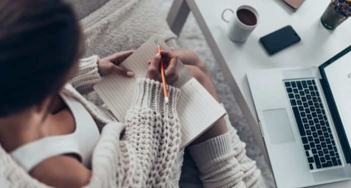 image of a Black woman with a notebook, pencil, and laptop