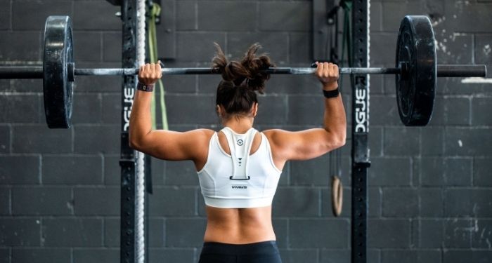 Image of the back of a Black person at a barbell stand