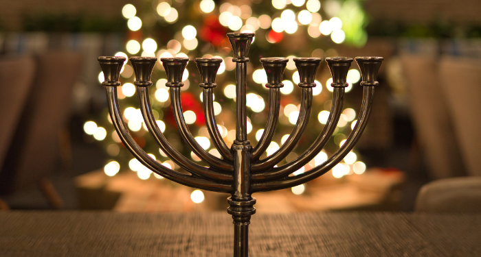 a photo of a menorah with Christmas tree lights in the background