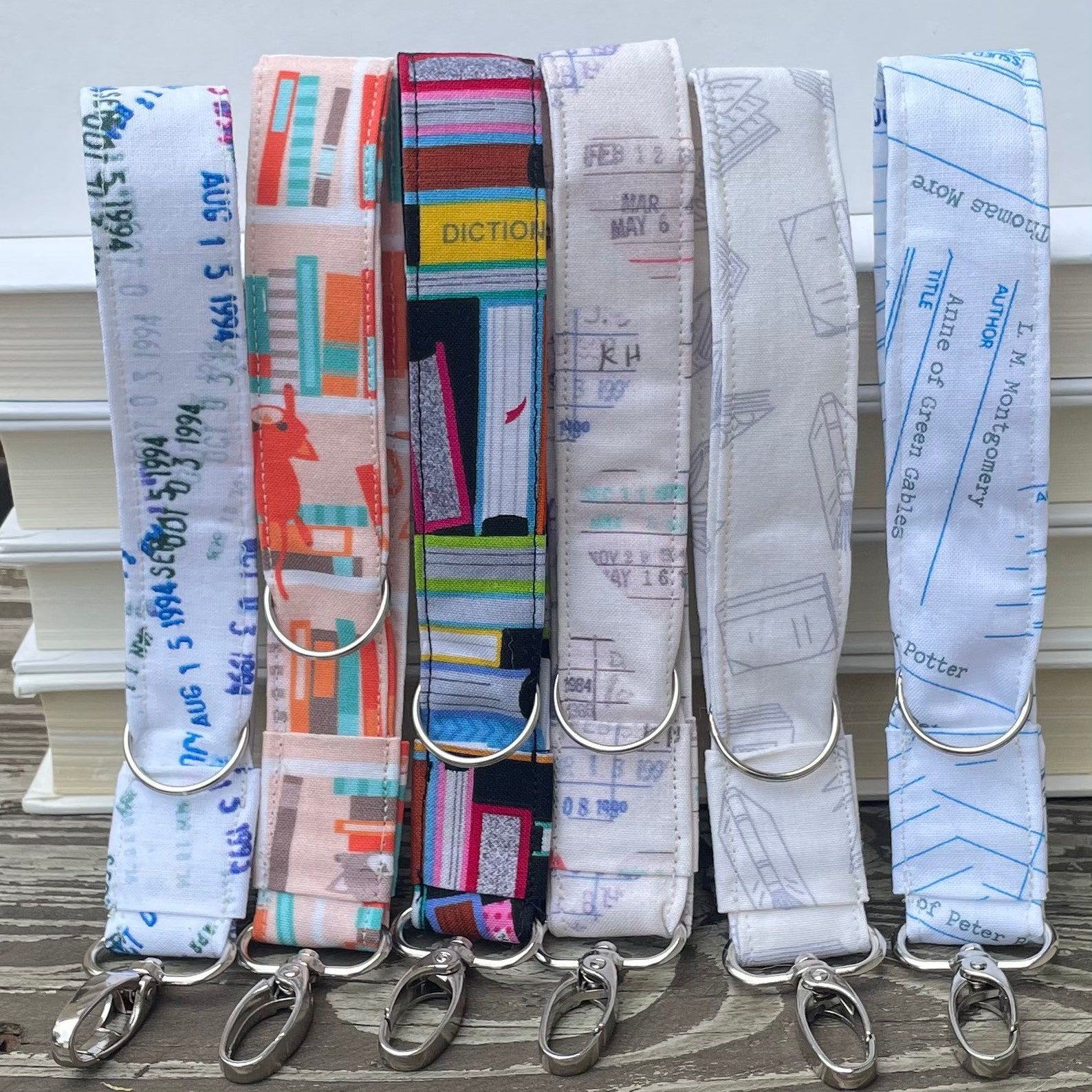 a bunch of handmade wristlet keychains in bookish patterns that include book and library due date cards