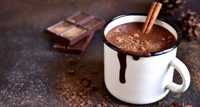 image of a white mug with hot chocolate and a cinnamon stick poking out from inside