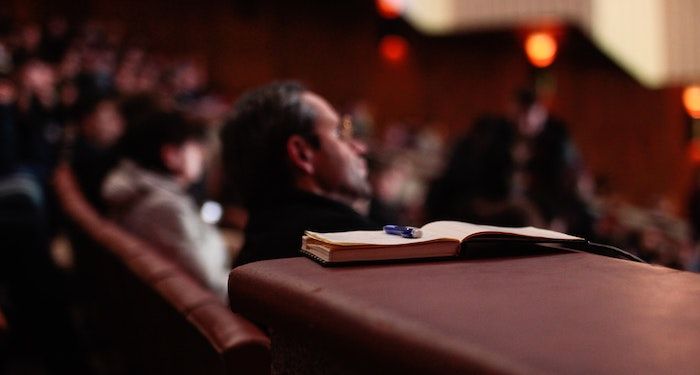 out of focus auditorium with notebook and pen in foreground