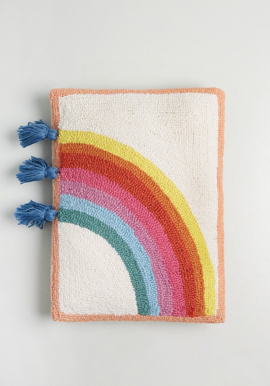 Image of a latch hook pillow with a bright rainbow across a white background. 