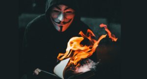 person in V for Vendetta mask burning a book
