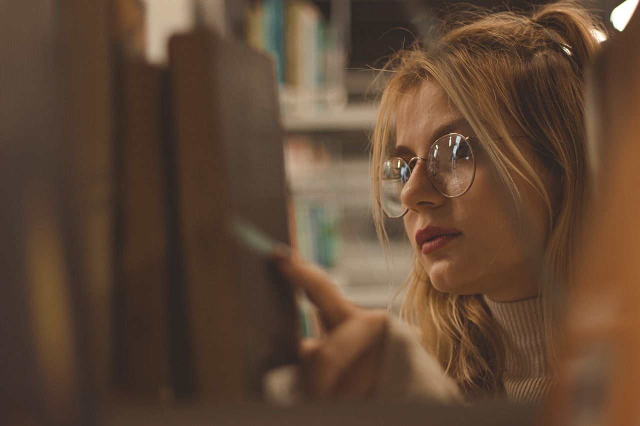 a photo of a woman looking through library shelves