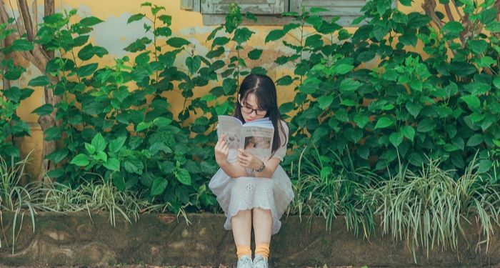 Asian woman sitting outside reading