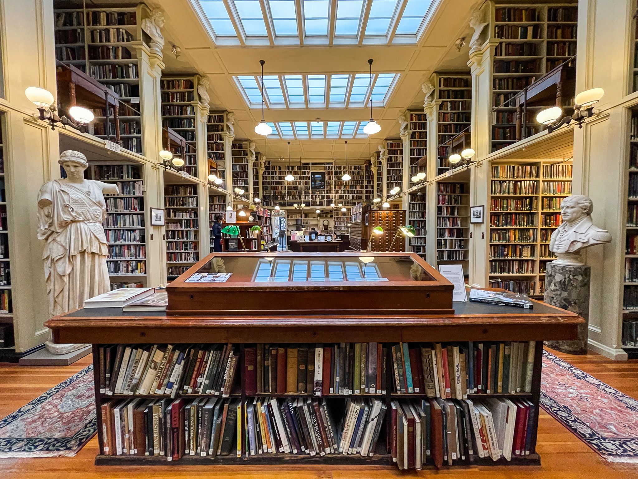 a photo of the entrance of the Providence Athenaeum, showing statues and a long row of shelves
