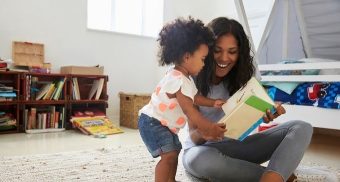 Image of a Black woman with a Black child in a bedroom full of books