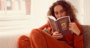 Image of a woman with brown skin reading a yoga book