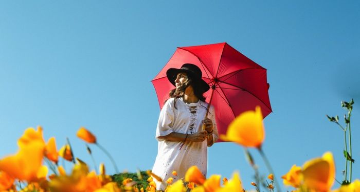 woman with red umbrella in a field of flowers