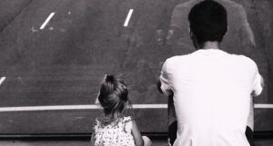 black and white pic of father daughter looking at a street and sitting down
