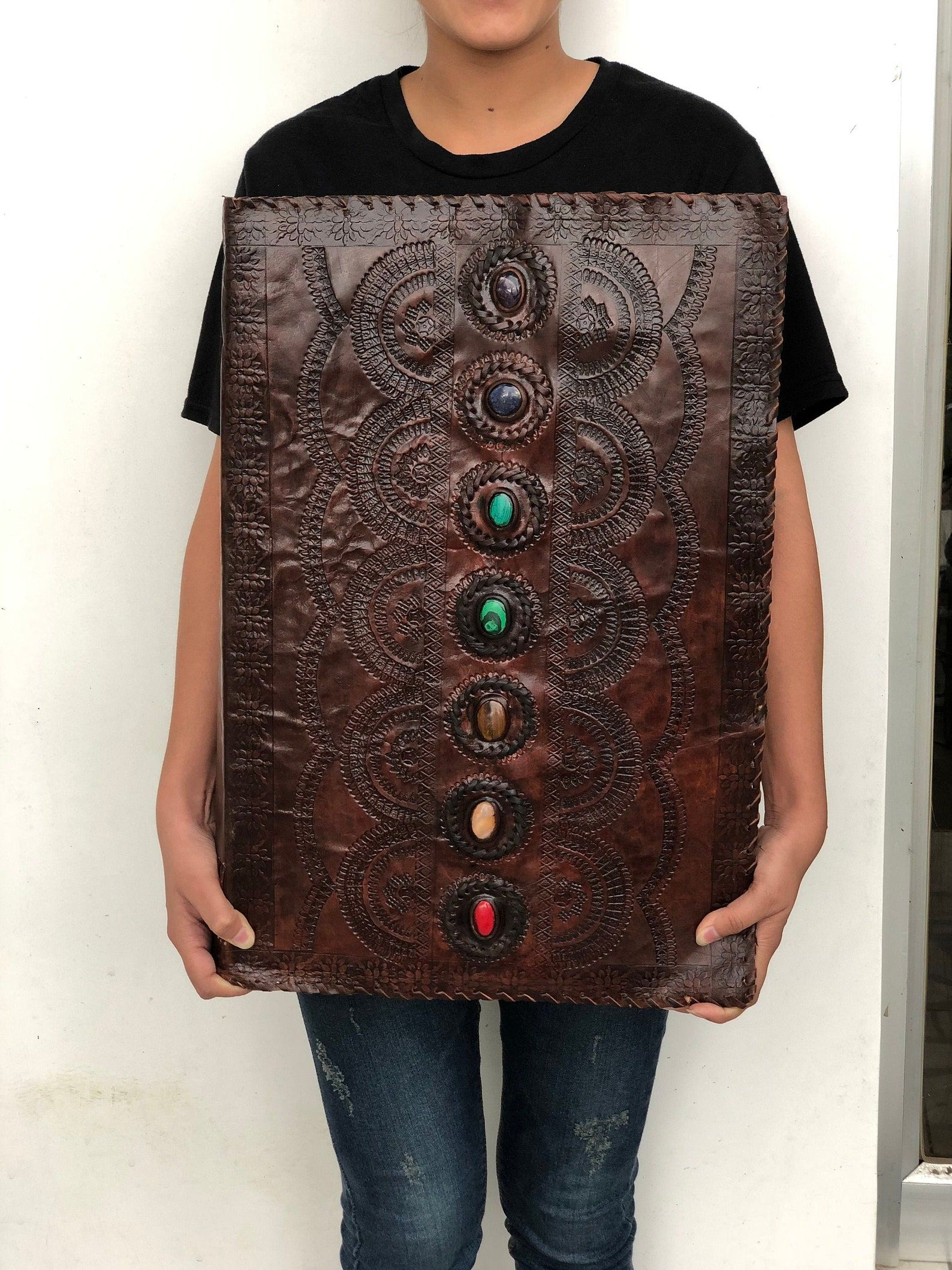Image of a giant leather journal with stones representing the 7 chakras down the center. 