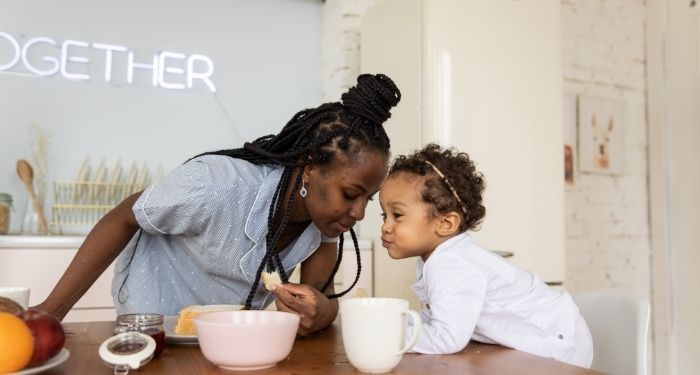 Image of a Black woman in the kitchen with a Black child