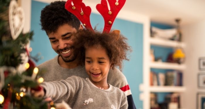 Image of a Black man and Black child at a Christmas tree