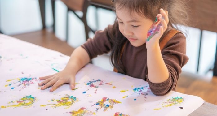 Image of an Asian child making handprint art