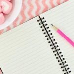 Image of an open notebook on a pink wavy background
