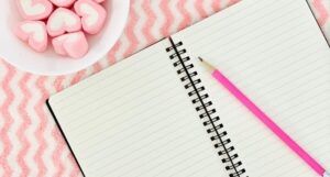 Image of an open notebook on a pink wavy background