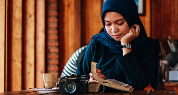 Image of woman in a hijab reading at a table