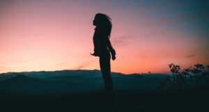 a woman in silhouette jumping at sunset