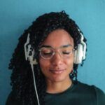 a Black woman with her eyes closed wearing a set of over-ear headphones