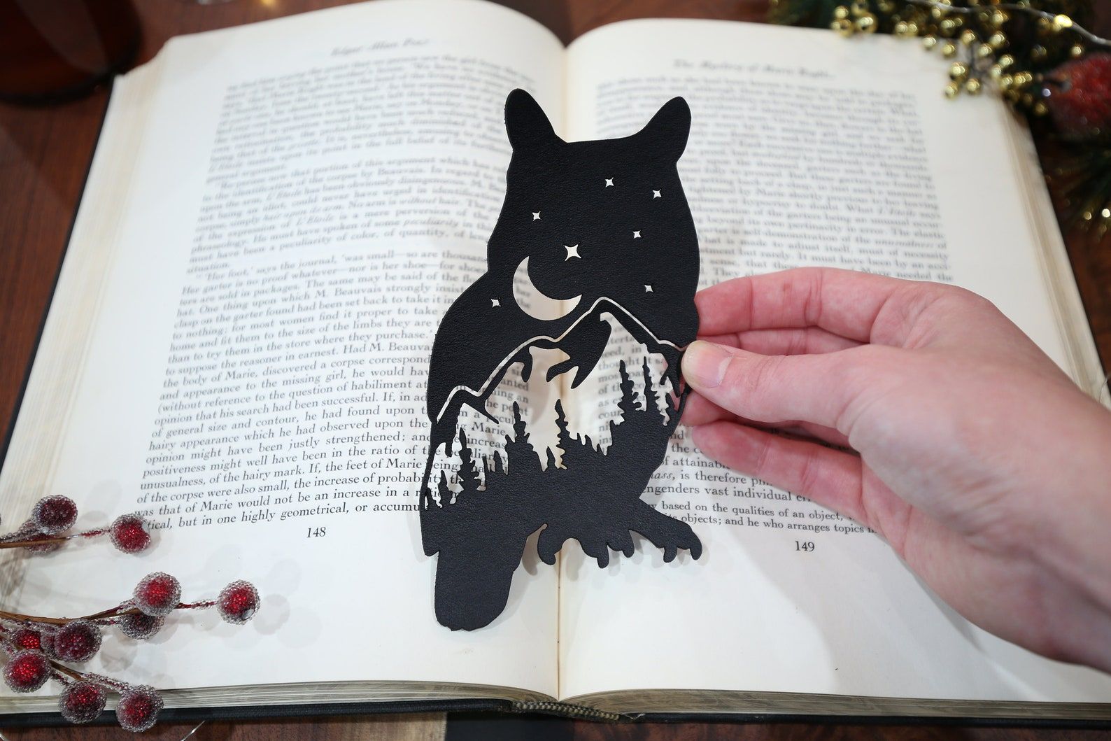 Image of a bookmark shaped like an owl. Inside, the owl includes a mountain range, evergreen trees, and a night sky. 