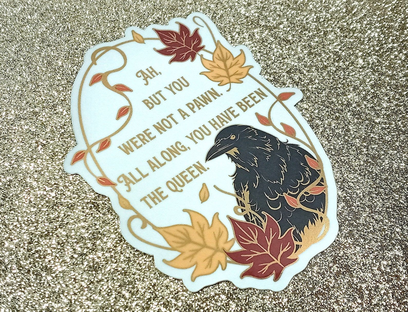 A sticker with a black raven, autumn leaves, and the text "Ah, but you were not a pawn. All along you have been the queen"